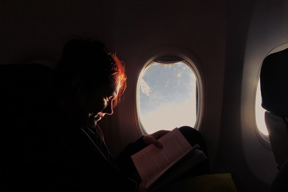 woman reading book in airplane