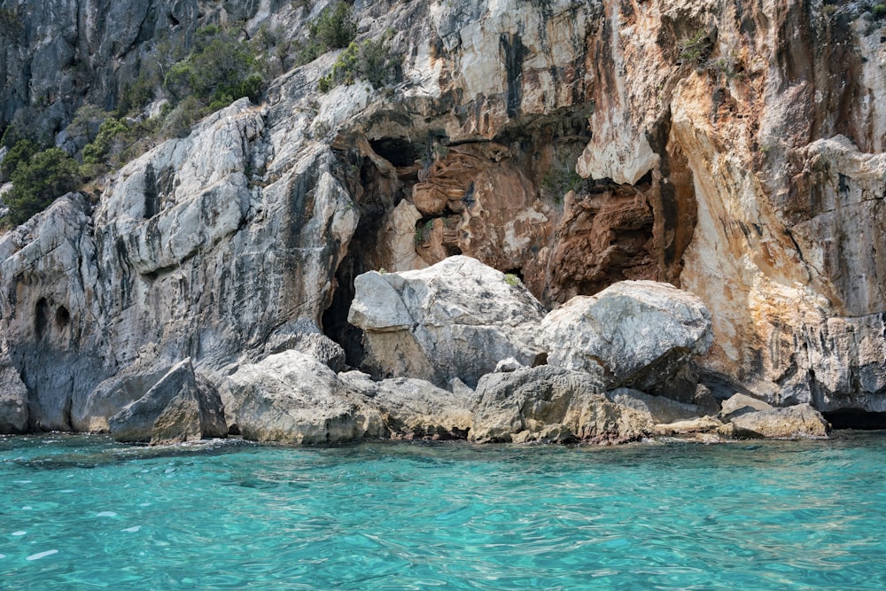 a rocky cliff with a blue body of water