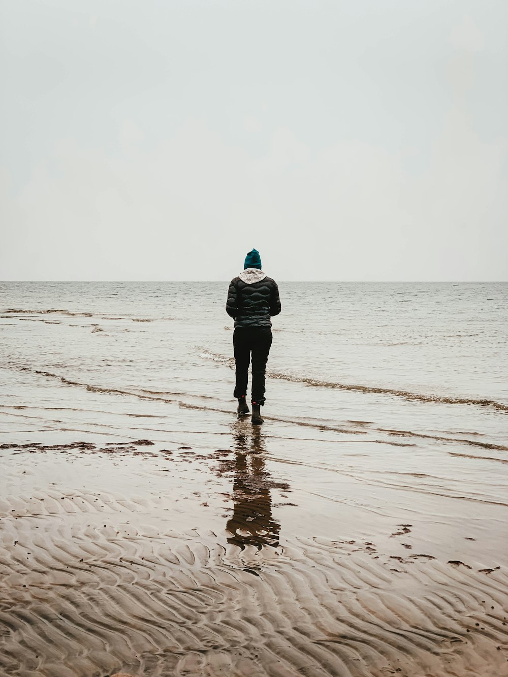 homem caminhando à beira-mar durante o dia