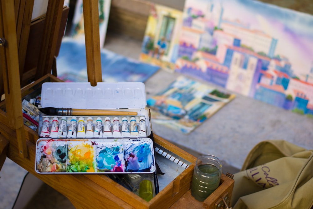 a wooden table topped with lots of art supplies