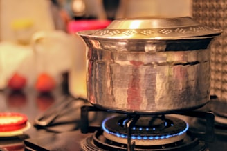 Close-up of a Midaz stainless steel cooker steaming on a gas stove with warm kitchen lighting.