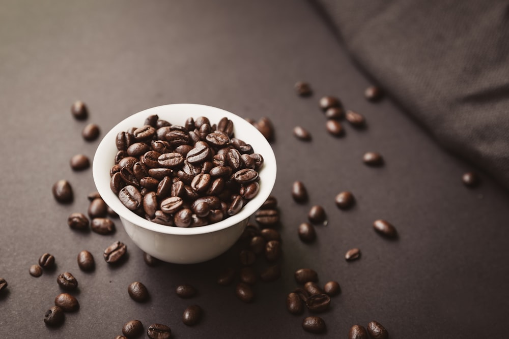 roasted coffee beans spilling out of white ceramic cup