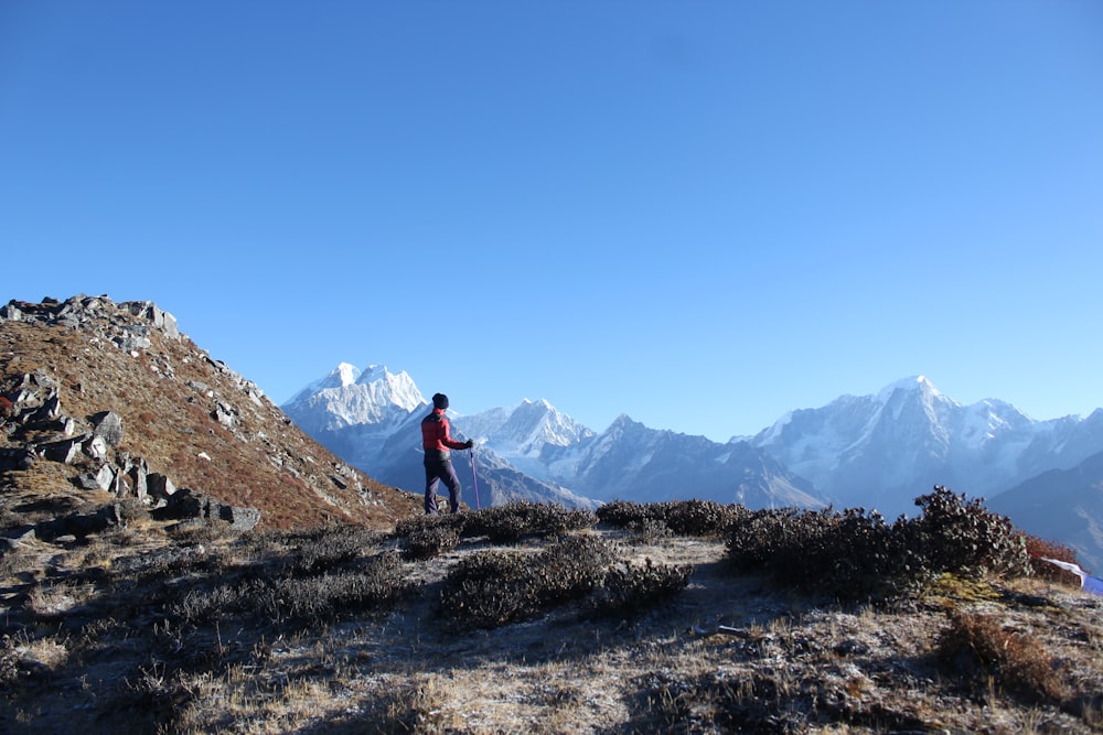 person standing on mountain under blue sky