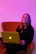 Smiling designer reviewing digital course materials on a sleek laptop with neon accents.