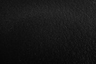 A black buff with subtle red metal-inspired patterns laid flat on a dark surface.