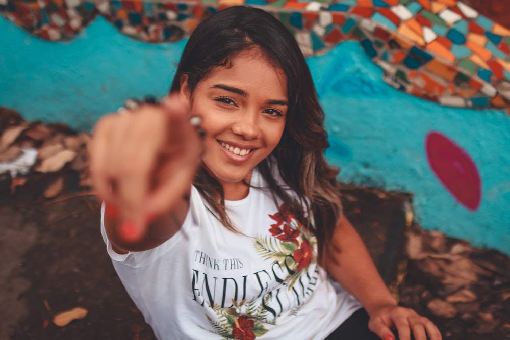 woman in white shirt pointing on camera