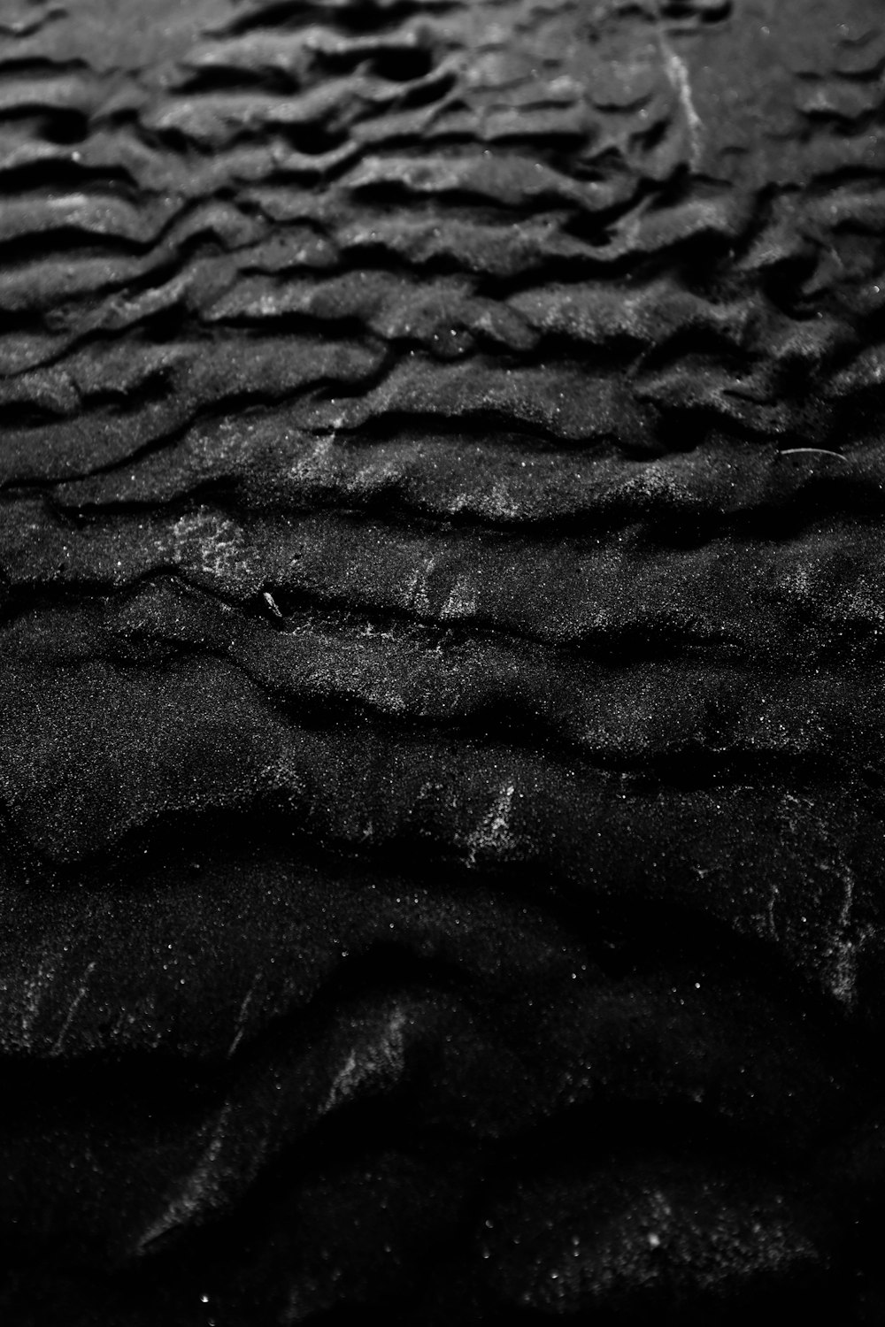 a black and white photo of waves in the sand