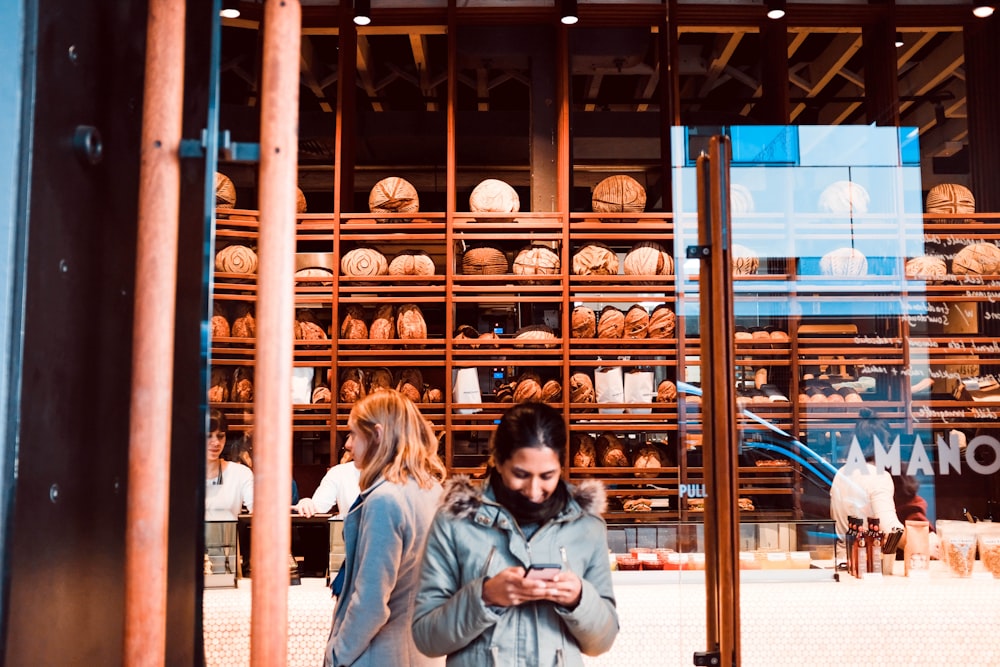 woman standing while using smartphone in front of store