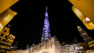 low angle view of fountain surrounded by buildings at night