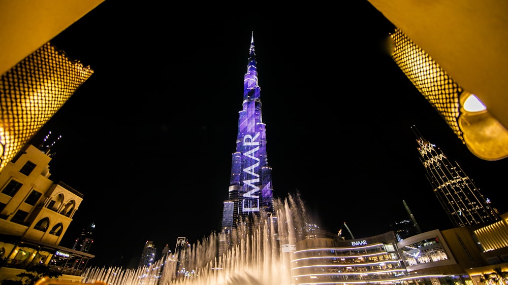 low angle view of fountain surrounded by buildings at night