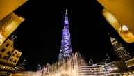 low angle view of fountain surrounded by buildings at night