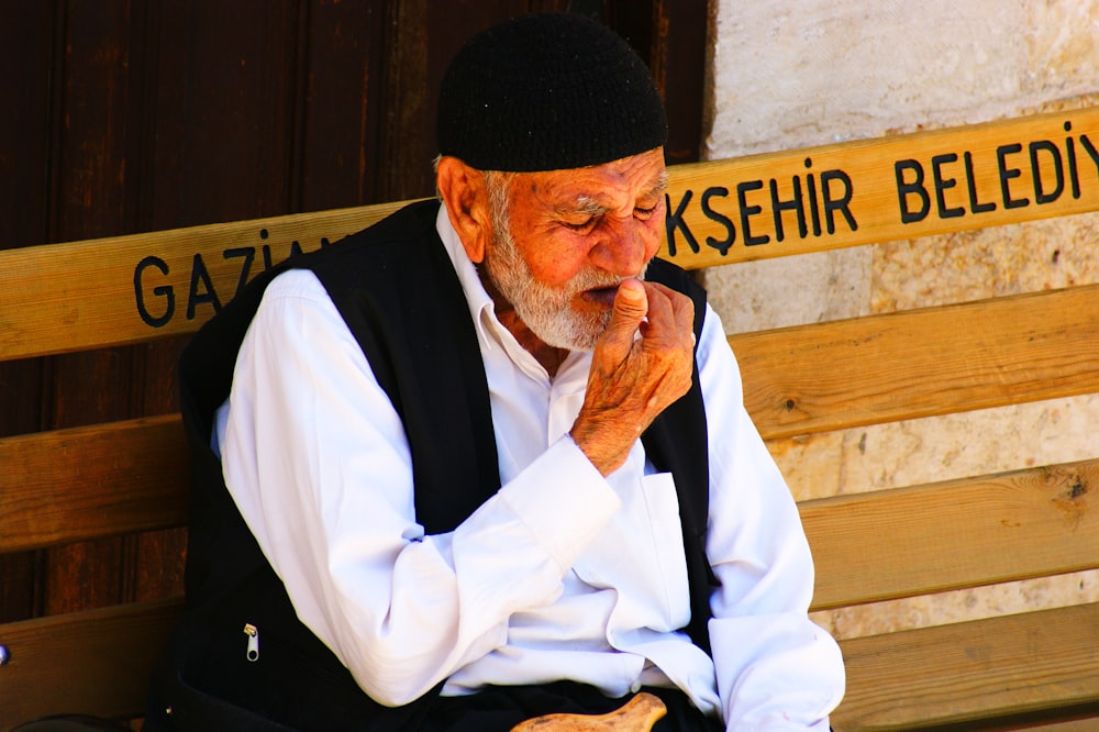 man wearing white dress shirt and black vest sitting on bench