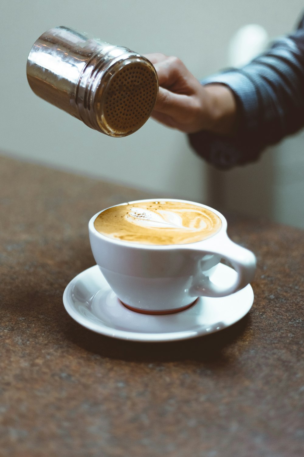 Person, die Schaum auf Cappuccino-Kaffee gießt