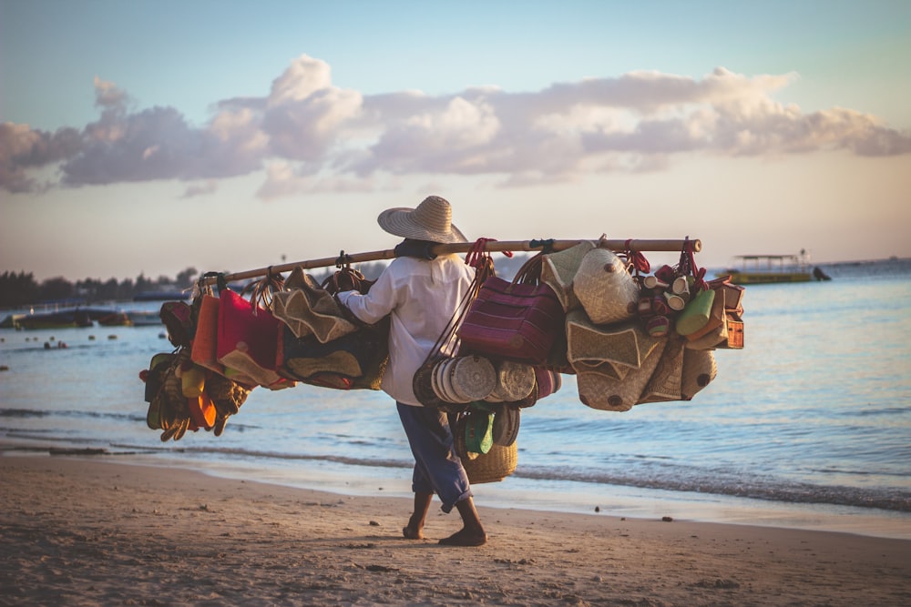 woman holding stick filled with bags near seashore