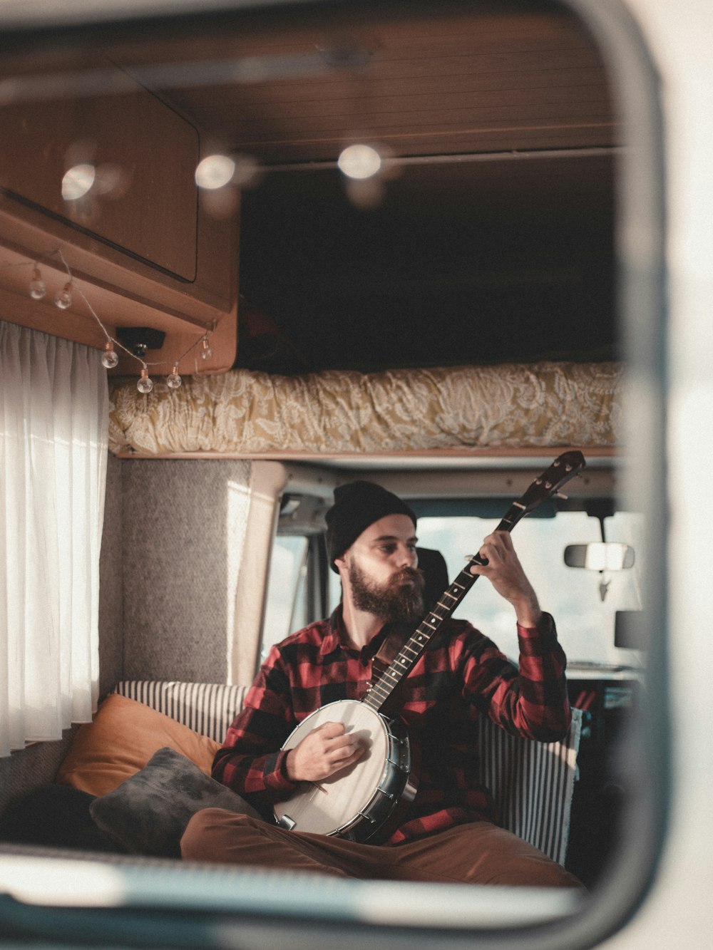 man sitting inside vehicle while playing mandoline