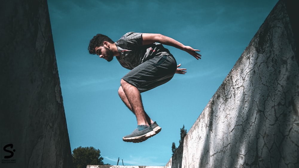 Man jumping over wall during daytime photo – Free Blue Image on Unsplash