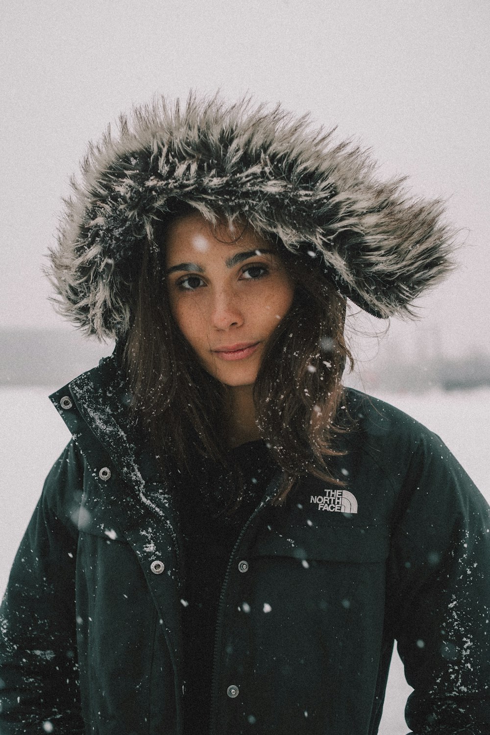 Frau in Schwarz und Weiß The North Face Kunstpelzmantel unter Schnee