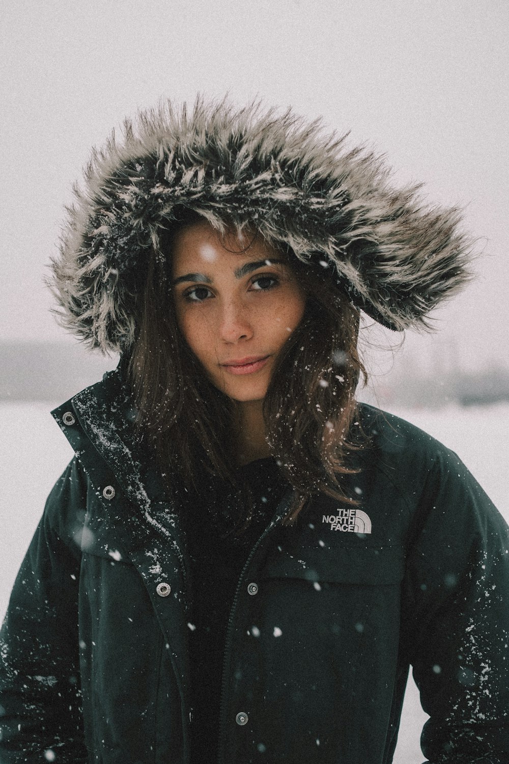 woman in black and white The North Face faux fur coat under snow