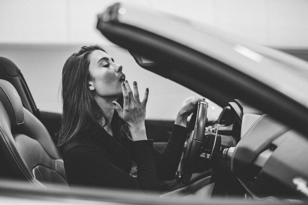 gayscale photography of woman sitting on vehicle