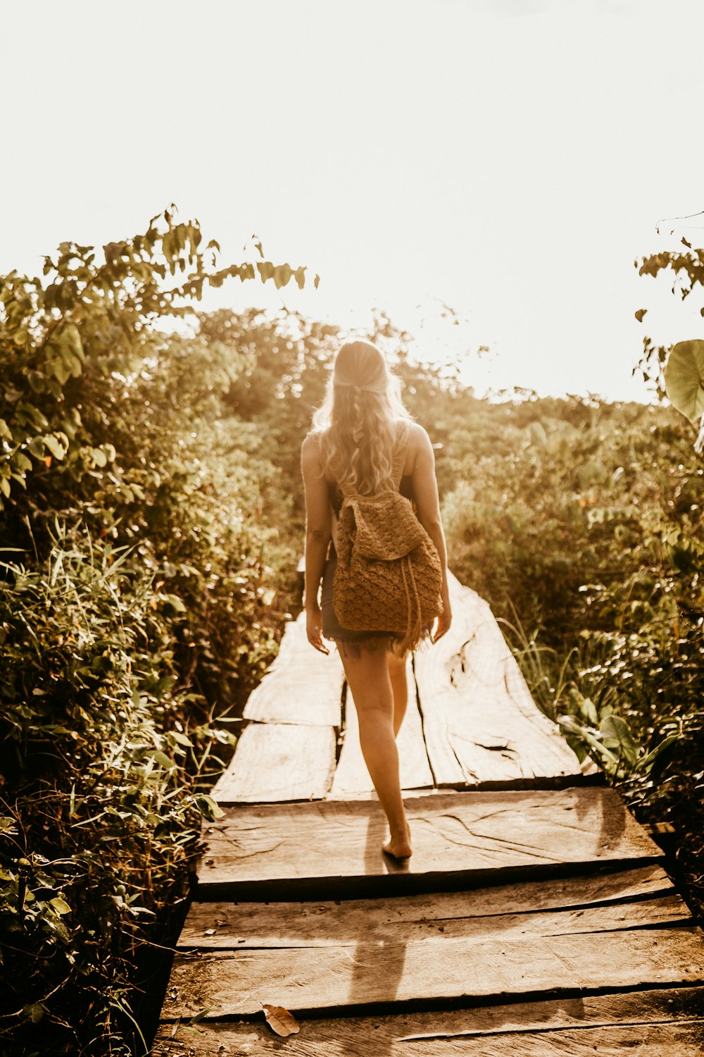 a woman walking across a wooden bridge in the woods
