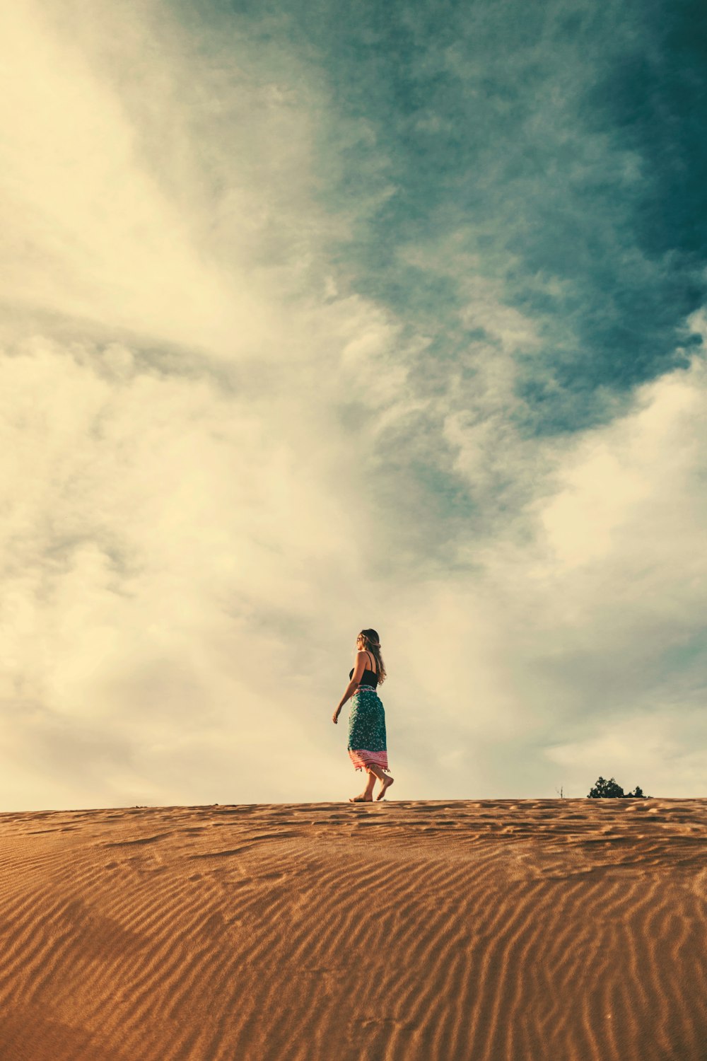 woman in skirt walks on sand barefoot