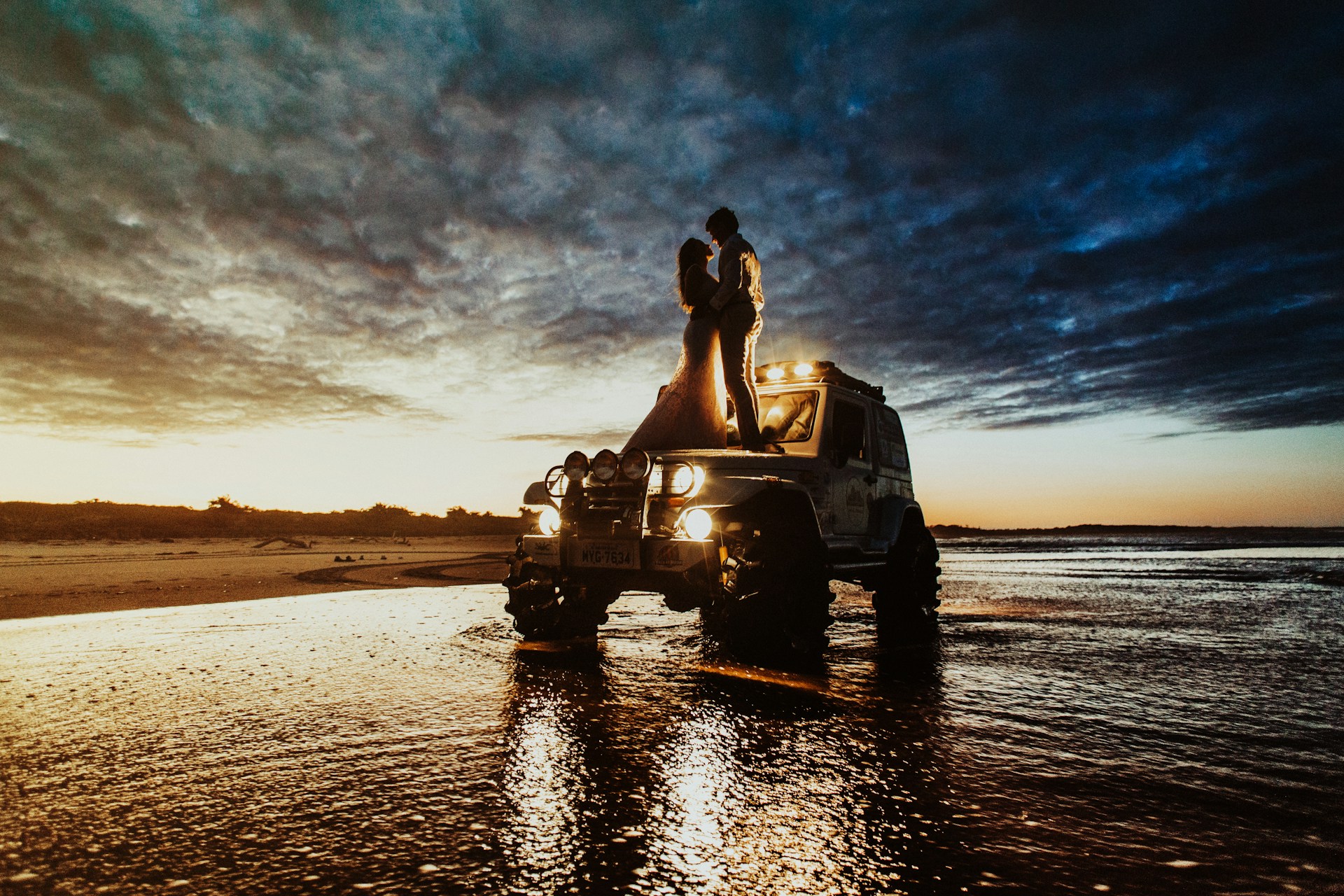 couple standing on SUV hood during golden hour