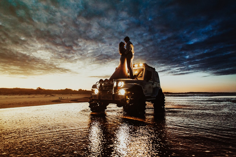 couple standing on SUV hood during golden hour