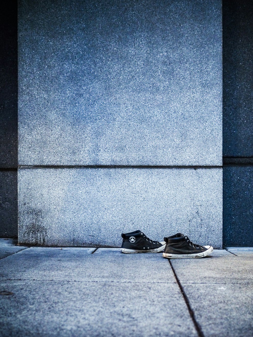 black-and-white high-top sneakers beside gray wall