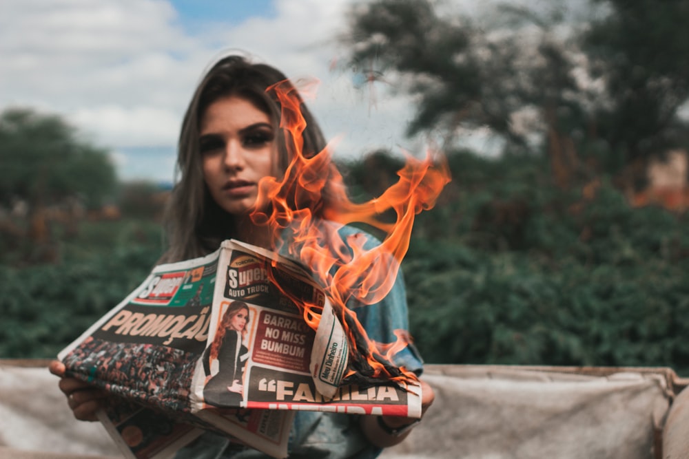 person holding burning newspaper