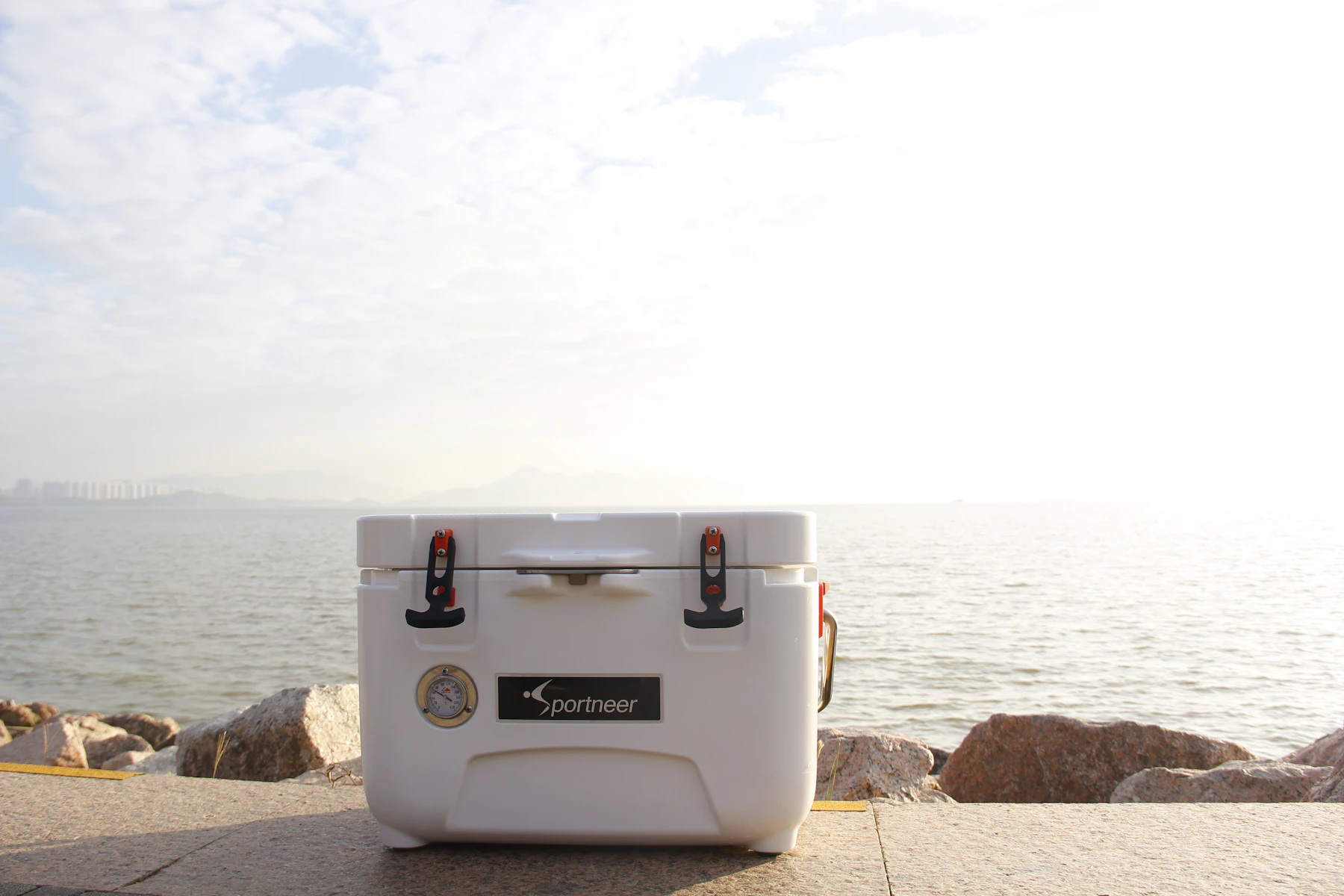 White hard cooler sitting outdoors near water