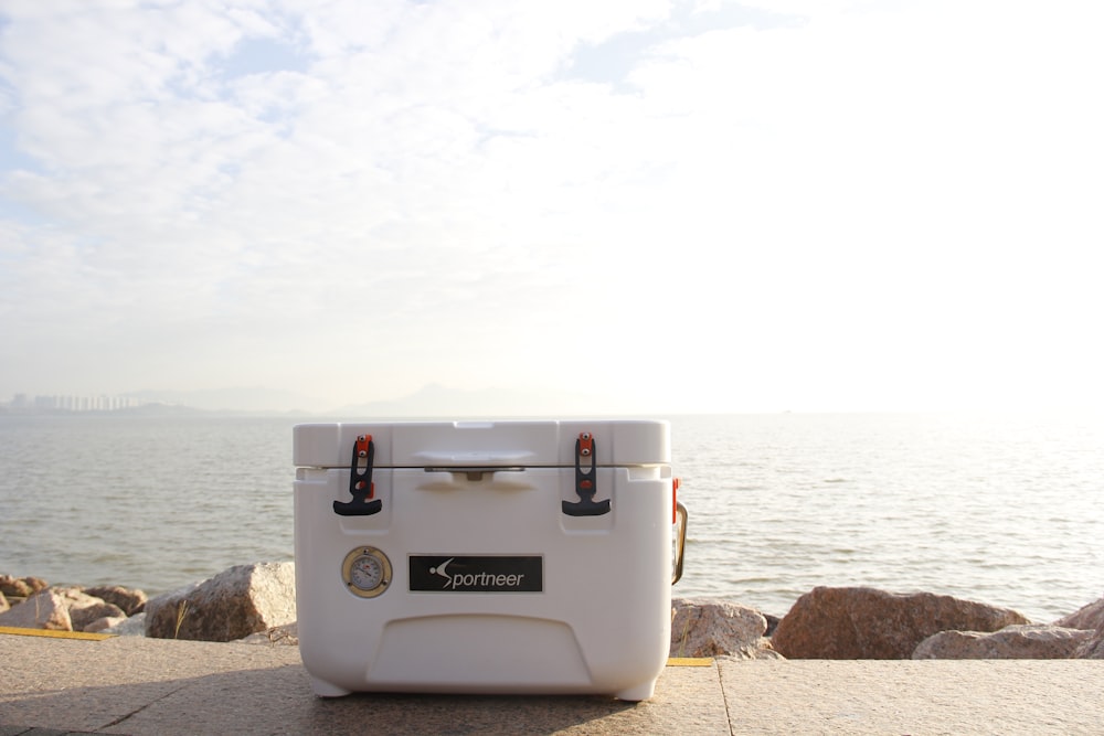 white cooler box on brown concrete pavement near body of water