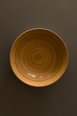 Close-up of a handcrafted wooden bowl made from reprocessed hardwood with visible grain patterns.