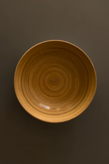 Close-up of a smooth wooden bowl with natural grain patterns on a minimalist white surface.