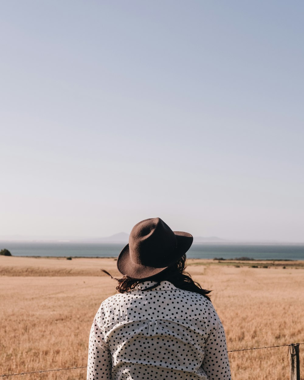 person in black and white polka dot top and brown hat