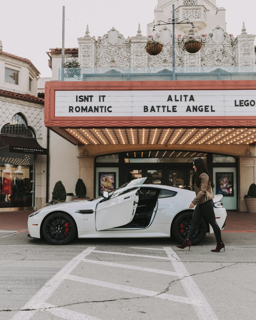 woman walking beside white sports car