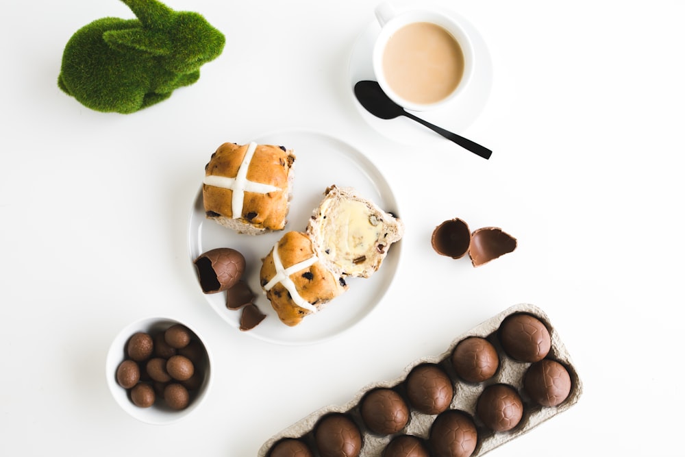 three pastries on white plate beside round saucer and teacup