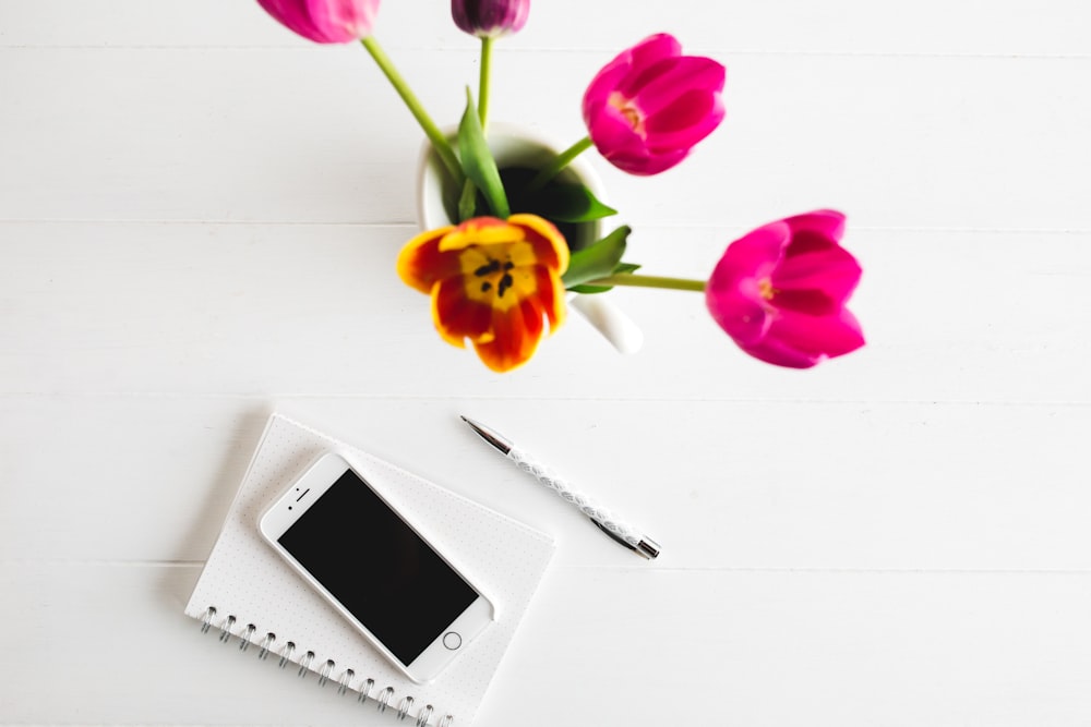 silver iPhone 6, click pen, and pink tulips
