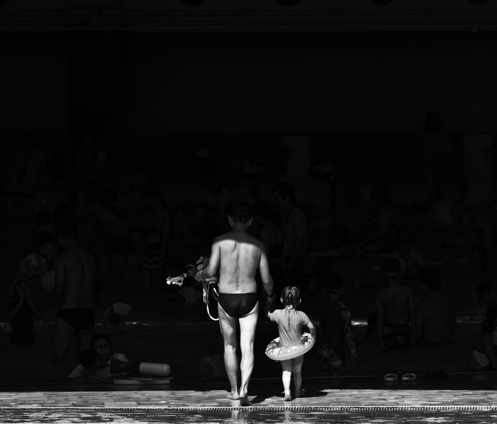 grayscale photography of man and girl standing to each other