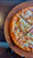 Close-up of a delicious New York-style pizza slice with melted cheese and fresh toppings on a rustic wooden table.