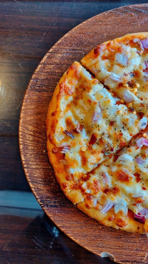 A close-up of a freshly baked pizza with melted cheese and vibrant toppings on a wooden table.