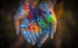 a pair of hands covered in colored powder