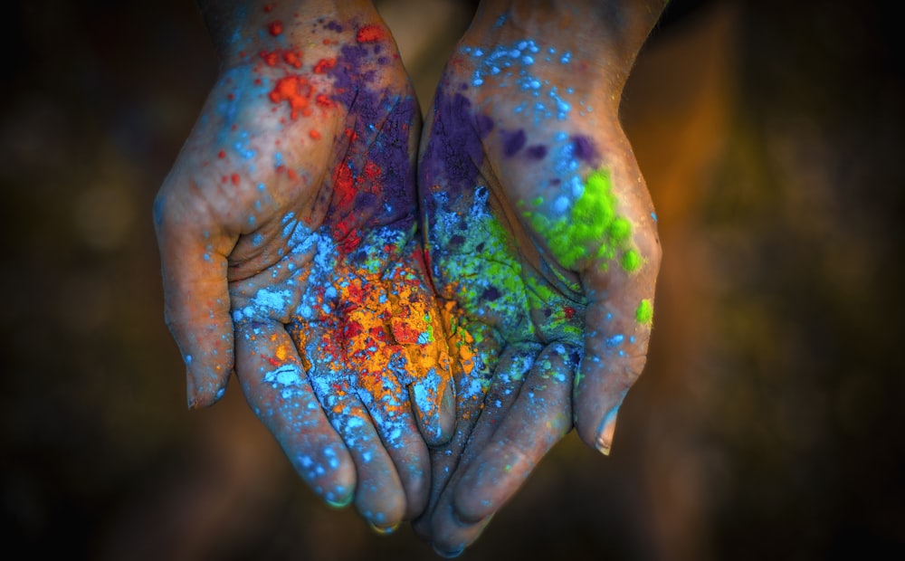 a pair of hands covered in colored powder