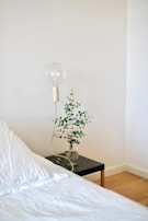 A minimalist bedroom corner with a simple bed frame, crisp white linens, and a small bedside lamp.