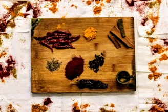 A rustic wooden board displaying an assortment of fresh spices and herbs used in cooking.