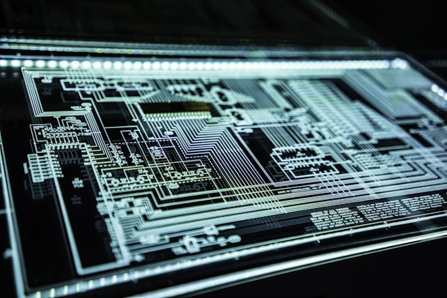Intricate circuit board design with a multitude of pathways, components, and connections depicted in a glowing pattern against a dark background.