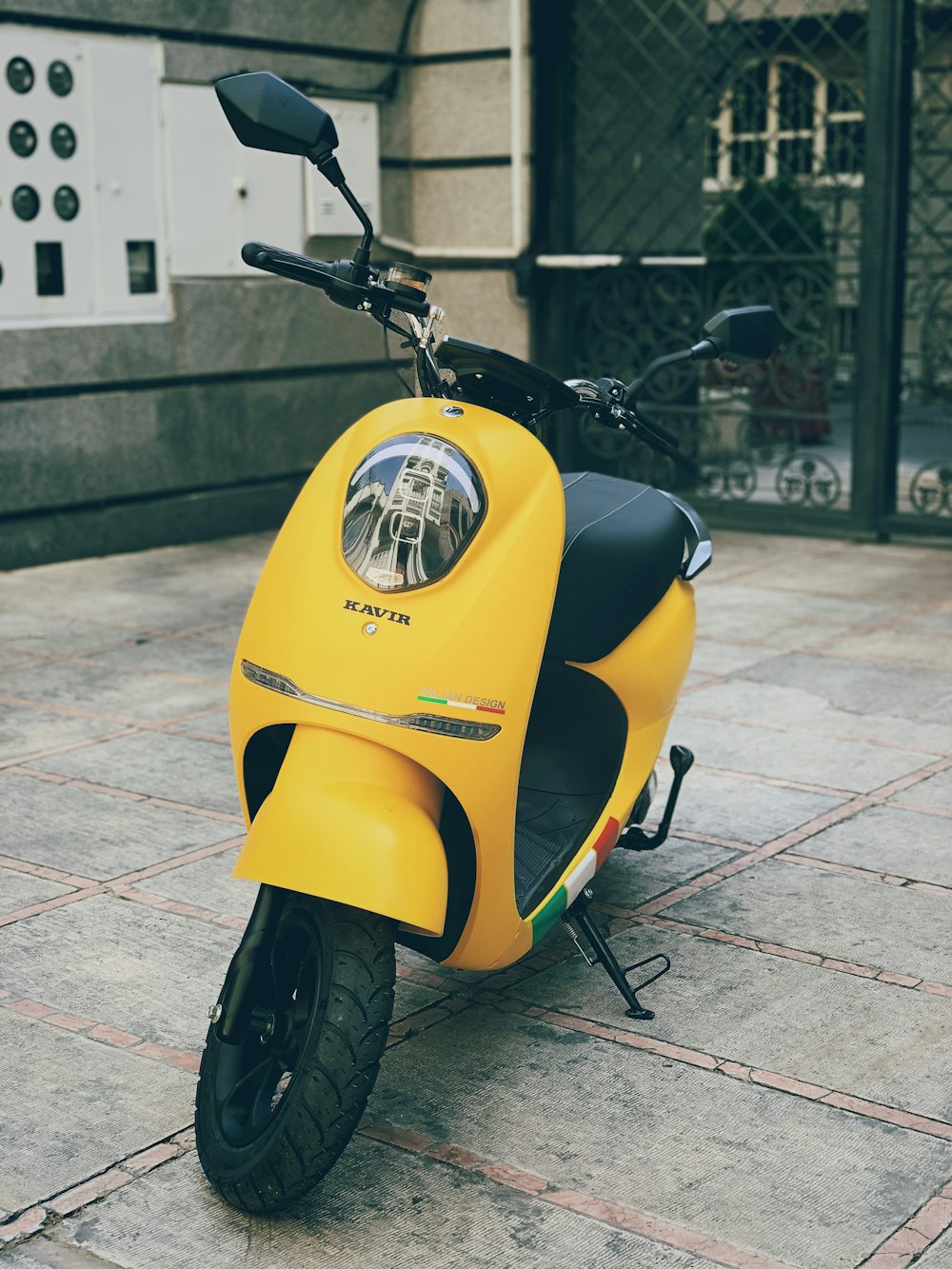 yellow motor scooter parked near gray metal chain fence