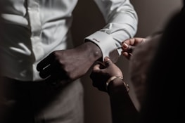 Hands of a leader adjusting a refined Provoca cufflink in a dimly lit room.