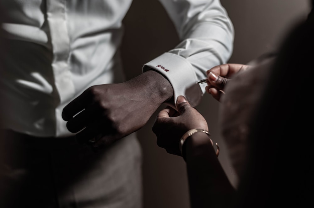 person putting pin on another person's white dress shirt