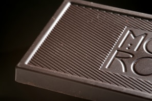 Close-up of glossy artisan chocolate bars with gold accents on a dark wooden table.