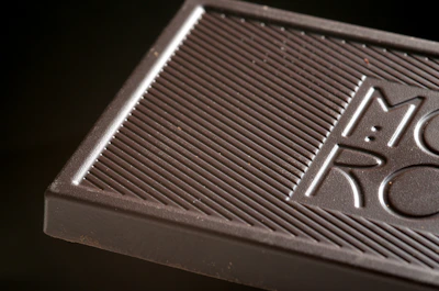 Close-up of a bespoke luxury chocolate piece with a finely embossed hotel logo in a warm bronze tone